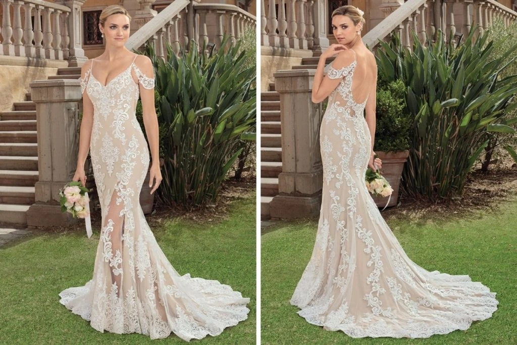 Sneak Peek: Casablanca Bridal Tester Event Front and back views of a fitted lace sheath wedding dress featuring delicate off-the-shoulder straps, a deep V-neckline, nude underlay, and an open back with an ornate lace train, photographed outdoors near stone steps and greenery.
