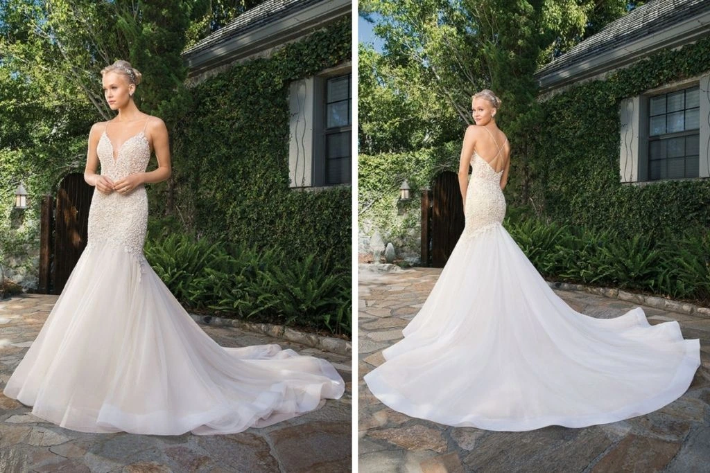 Sneak Peek: Casablanca Bridal Tester Event Front and back views of a mermaid-style wedding gown featuring a beaded lace bodice, delicate spaghetti straps, and a dramatic tulle train, photographed outdoors beside ivy-covered walls.