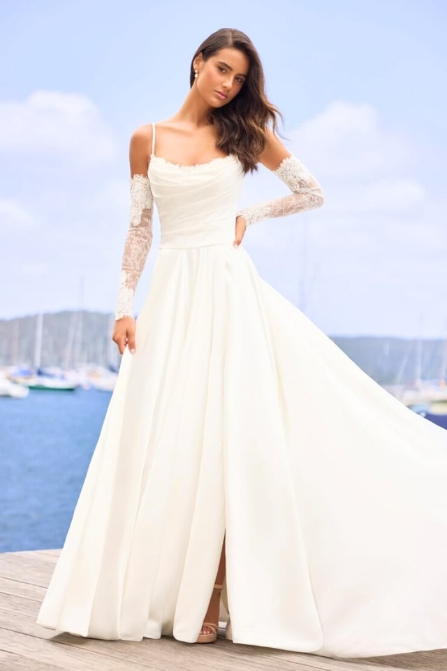 A-line wedding dress with scoop neckline, detachable lace gauntlet sleeves, and full skirt with slit.