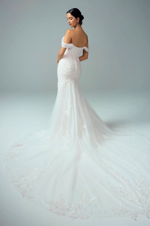 Off-the-shoulder sparkling fit and flare wedding dress with lace appliqués, ruched bodice, and long train.