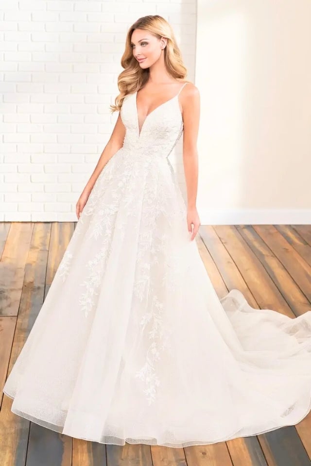 Bride wearing 122174 Willow Bloom A-line wedding gown with lace and sparkle tulle, standing in a sunlit room with wood floors.