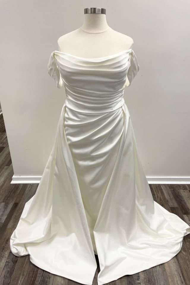 Ruched Satin Off-the-Shoulder Wedding Dress Tara Blake Ivory satin off-the-shoulder wedding dress with ruched bodice and flowing A-line skirt on mannequin