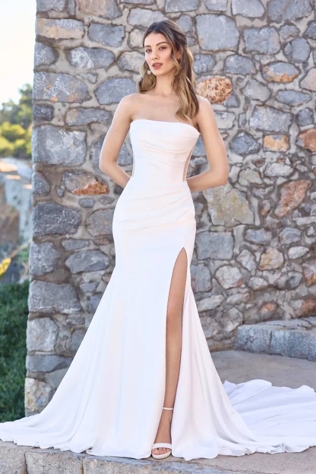 Strapless satin fit and flare wedding dress with draped bodice, skirt slit, and illusion back.