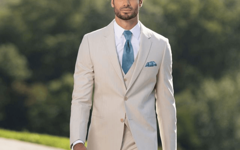 groom wearing a beige tux with a blue tie