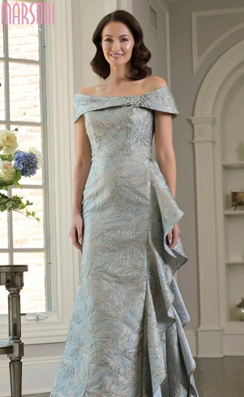 Marsoni off-the-shoulder mother of the bride gown in textured jacquard fabric featuring a fitted silhouette, folded neckline, and cascading ruffle skirt detail in soft blue-gray tones