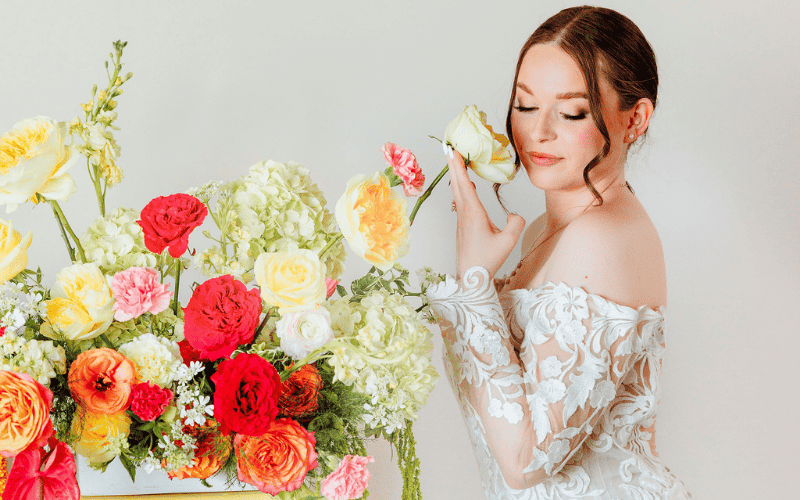 bride smelling a flower and wearing a laced long sleeve wedding dress