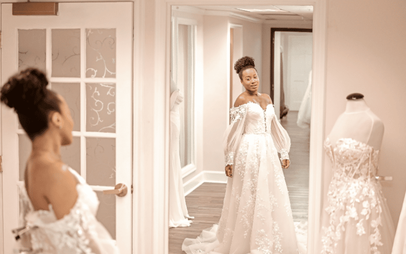 How to Find the Perfect Wedding Dress Beyond Your Pinterest Board bride in front of the mirror wearing her wedding gown with sleeves